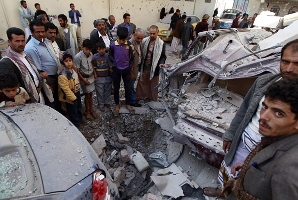 Yemenis look at destruction in the street following air strikes on the capital, Sanaa, on Tuesday (AFP photo)